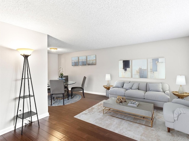 living area featuring a textured ceiling, dark wood-style flooring, and baseboards