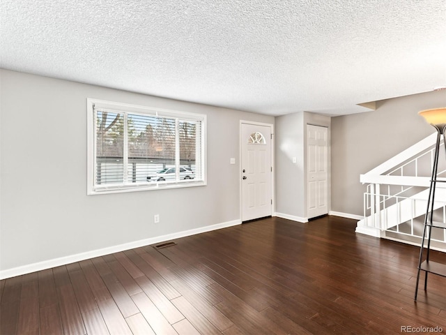 entryway featuring visible vents, a textured ceiling, baseboards, and wood finished floors