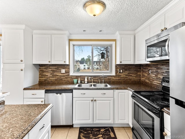 kitchen featuring stainless steel appliances, white cabinetry, a sink, and light tile patterned floors