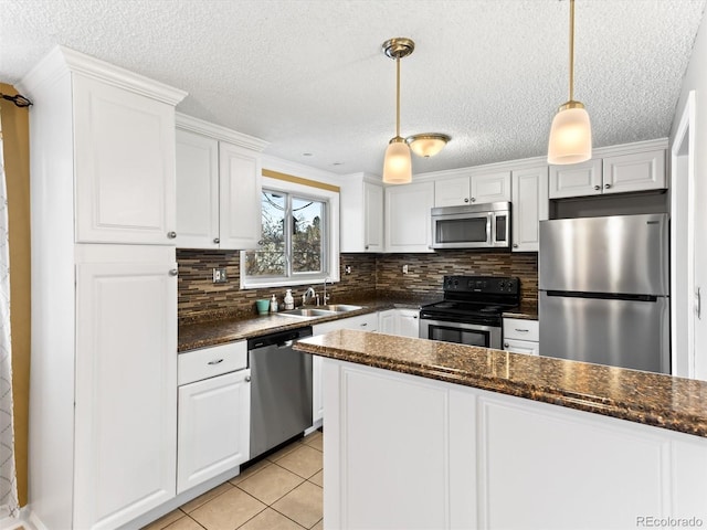 kitchen with stainless steel appliances, backsplash, white cabinetry, a sink, and light tile patterned flooring