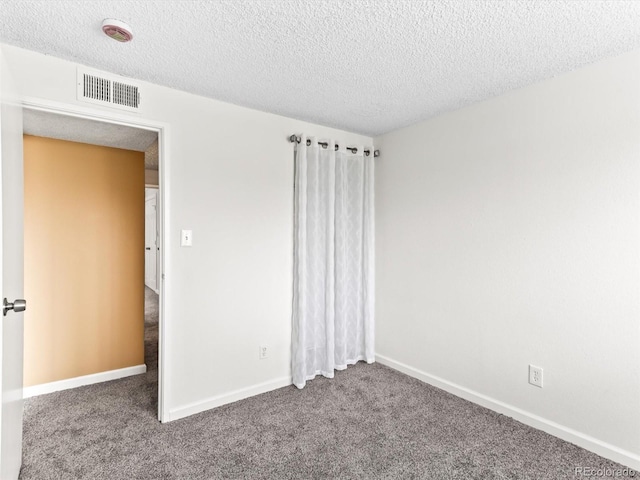 unfurnished bedroom featuring baseboards, visible vents, a textured ceiling, and carpet flooring