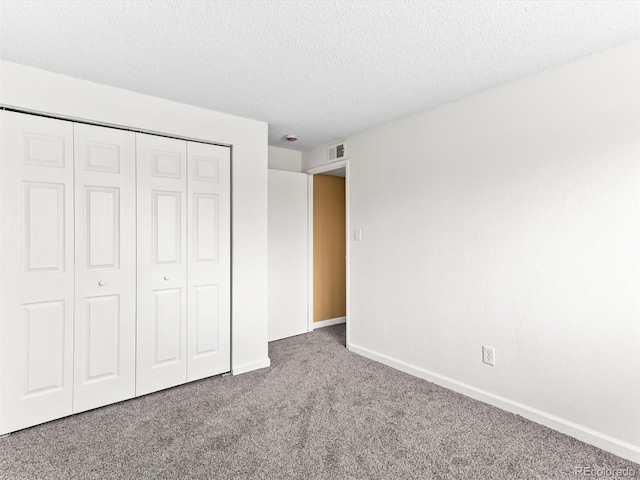 unfurnished bedroom featuring a closet, a textured ceiling, baseboards, and carpet flooring