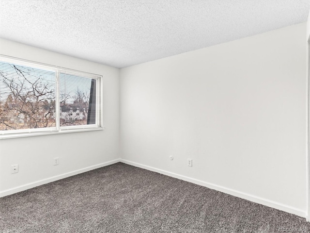 empty room featuring baseboards, dark colored carpet, and a textured ceiling