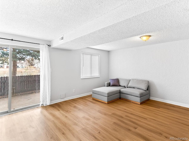 unfurnished room featuring visible vents, a textured ceiling, baseboards, and wood finished floors