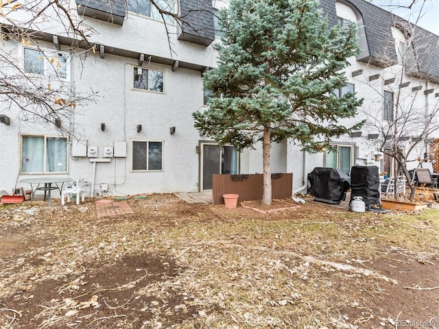 rear view of house featuring stucco siding