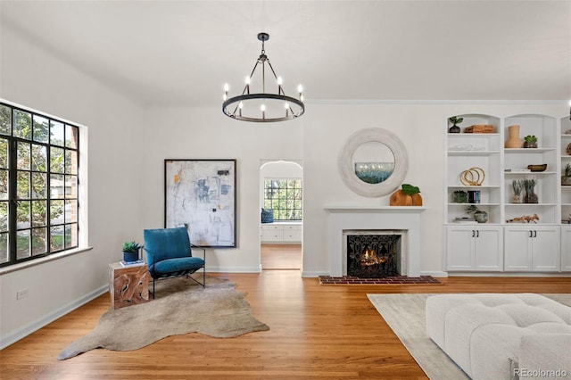 sitting room featuring an inviting chandelier, built in features, and light hardwood / wood-style floors