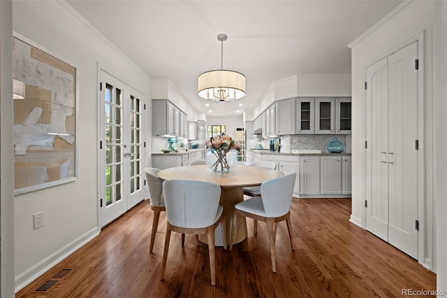 dining area with hardwood / wood-style flooring, crown molding, and french doors