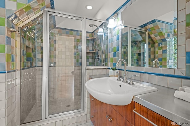 bathroom with vanity, tasteful backsplash, tile walls, and walk in shower