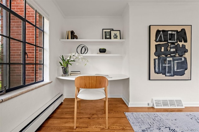 office space featuring a baseboard heating unit, crown molding, built in desk, and plenty of natural light