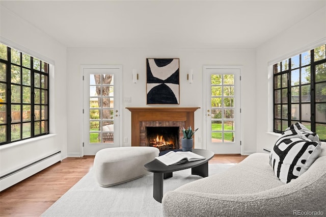 sitting room with a baseboard heating unit, a fireplace, and light wood-type flooring