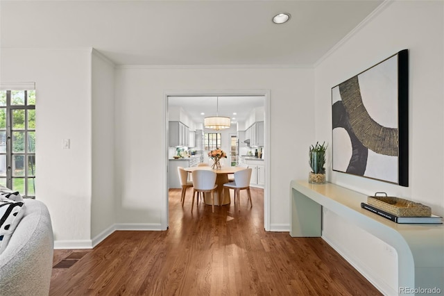 hallway with ornamental molding, hardwood / wood-style floors, and an inviting chandelier