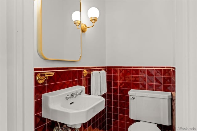 bathroom with toilet, sink, and tile walls