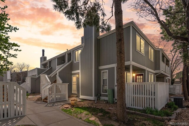exterior space with a chimney, central AC unit, and fence