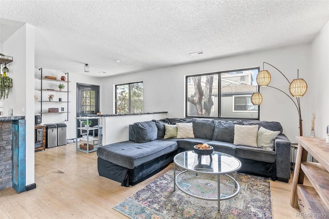 living room with light wood-style flooring, a textured ceiling, and visible vents
