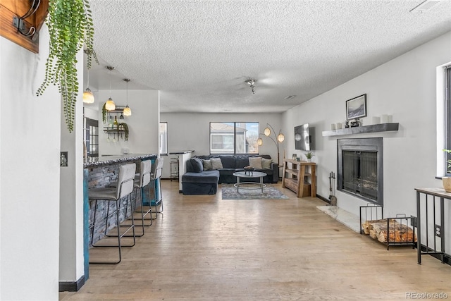 living area with a premium fireplace, a textured ceiling, and wood finished floors