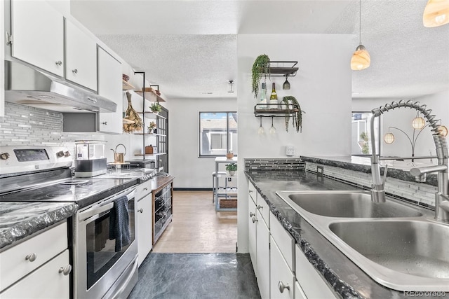 kitchen with under cabinet range hood, a textured ceiling, stainless steel range with electric cooktop, and a sink