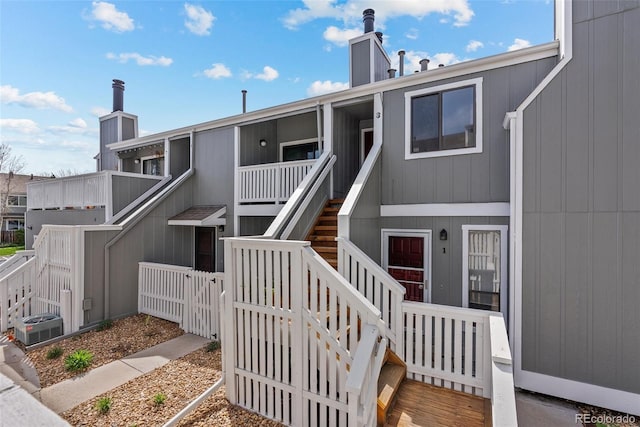 exterior space with a gate, central AC, fence, a chimney, and stairs