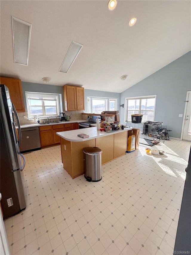 kitchen with kitchen peninsula, appliances with stainless steel finishes, lofted ceiling, and a healthy amount of sunlight