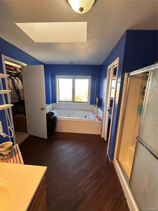 bathroom featuring a skylight, separate shower and tub, hardwood / wood-style floors, a textured ceiling, and vanity