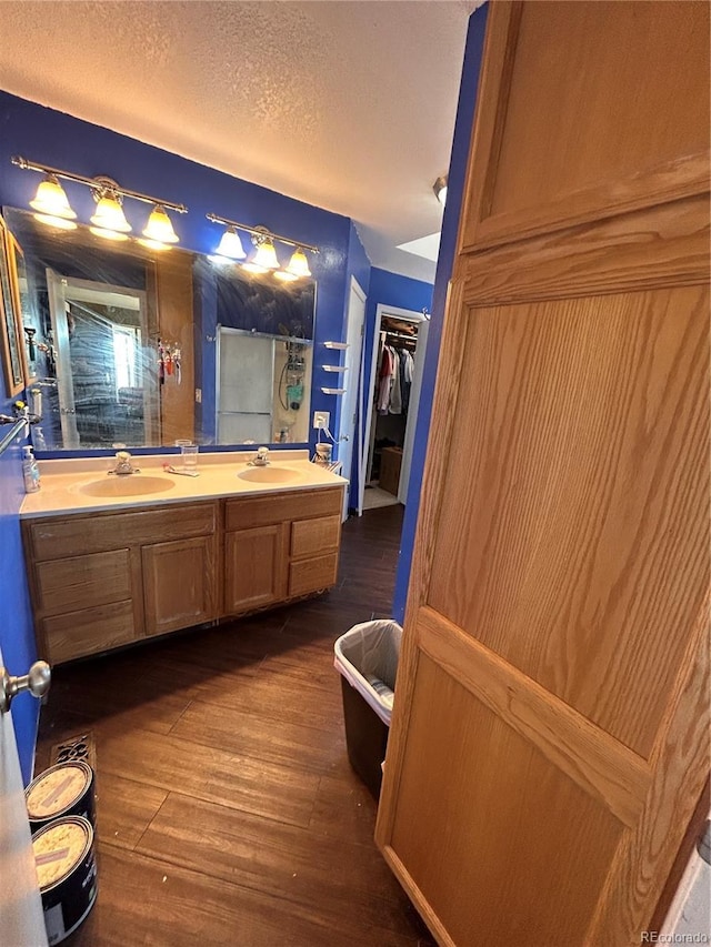 bathroom featuring vanity, wood-type flooring, a textured ceiling, and walk in shower