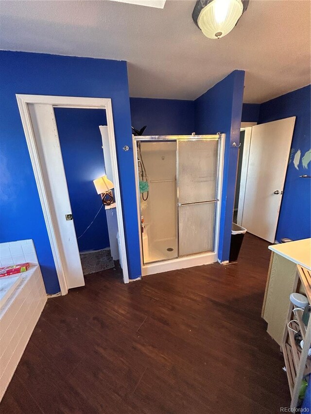 interior space featuring a tub to relax in, a textured ceiling, and hardwood / wood-style flooring