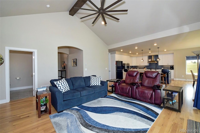 living room featuring sink, beam ceiling, high vaulted ceiling, and light hardwood / wood-style flooring