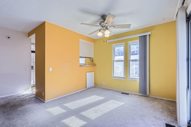 unfurnished room featuring ceiling fan, light colored carpet, and a textured ceiling