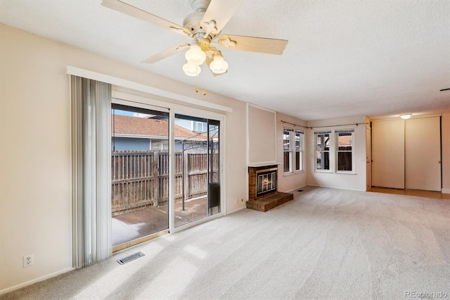 unfurnished living room featuring light carpet, a textured ceiling, and a fireplace