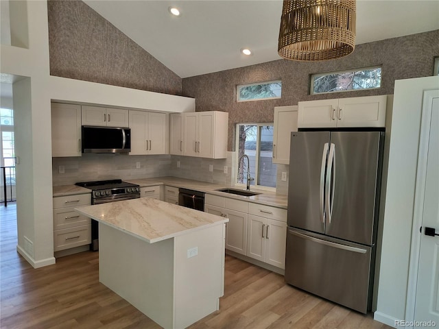 kitchen with stainless steel appliances, a sink, a center island, white cabinets, and high vaulted ceiling