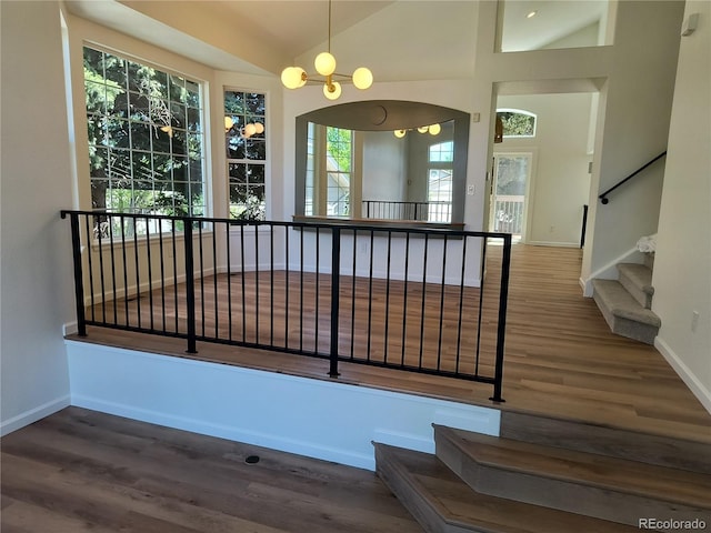 unfurnished dining area featuring vaulted ceiling, wood finished floors, baseboards, and stairway