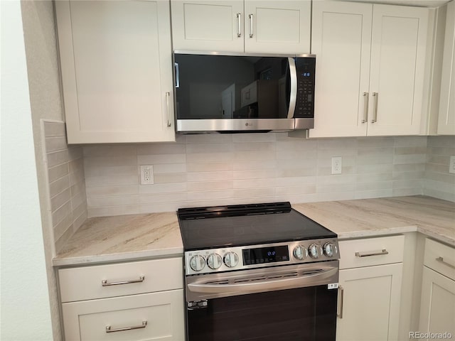 kitchen with stainless steel appliances, white cabinets, tasteful backsplash, and light stone countertops