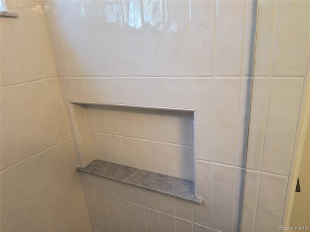 bathroom view of tiled shower and tile walls