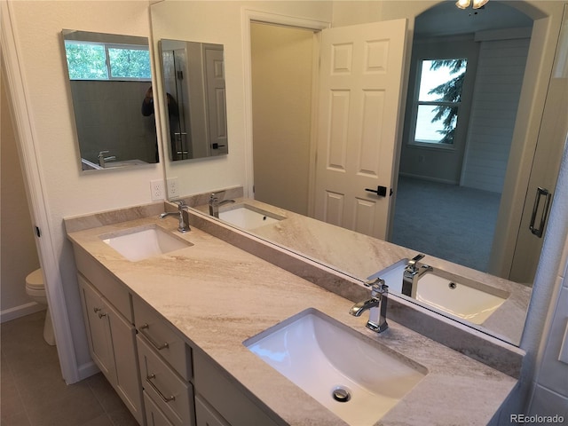 full bathroom with toilet, double vanity, and tile patterned flooring