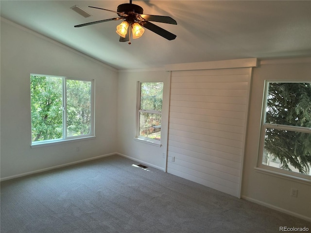 carpeted empty room with vaulted ceiling, baseboards, ceiling fan, and crown molding