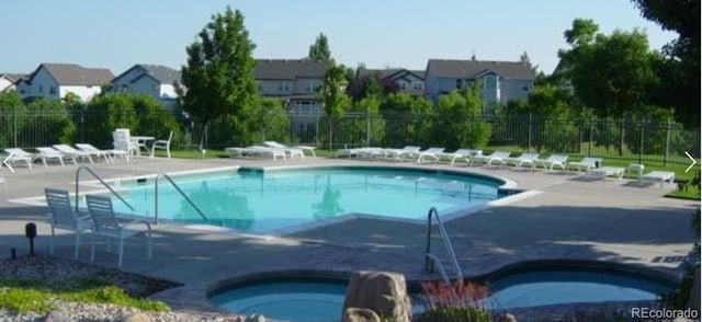 community pool featuring fence, a patio, and a residential view