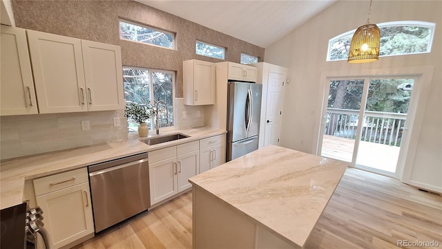 10538 Tiger Chase, Lone Tree, CO 80124 - kitchen with stainless steel appliances, high vaulted ceiling, light wood finished floors, tasteful backsplash, and decorative light fixtures