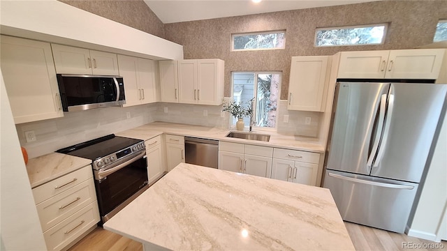 10538 Tiger Chase, Lone Tree, CO 80124 - kitchen featuring appliances with stainless steel finishes, tasteful backsplash, white cabinets, vaulted ceiling, and light wood-type flooring