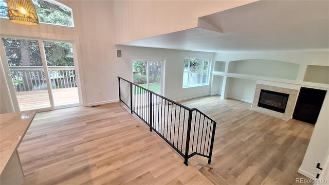 10538 Tiger Chase, Lone Tree, CO 80124 - unfurnished living room with light wood-type flooring, a towering ceiling, a tile fireplace, and built in features