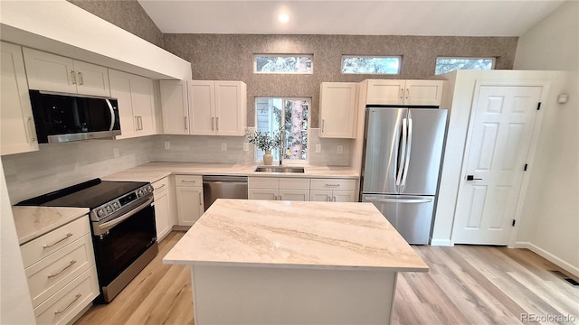 10538 Tiger Chase, Lone Tree, CO 80124 - kitchen featuring appliances with stainless steel finishes, light wood finished floors, a center island, white cabinetry, and tasteful backsplash