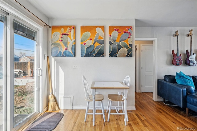 dining space with baseboards, light wood-style floors, and a healthy amount of sunlight