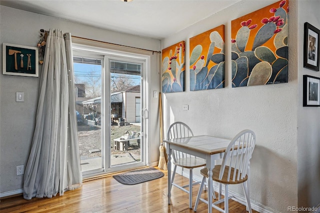 dining space featuring wood finished floors, baseboards, and a textured wall