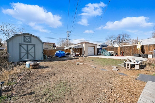 view of yard with an outbuilding, fence, driveway, a detached garage, and a storage shed