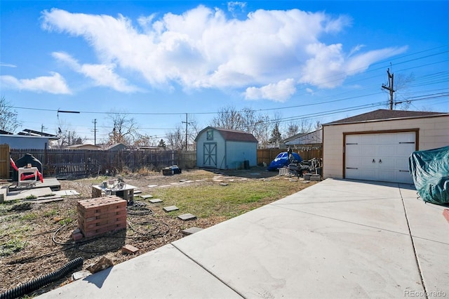 view of yard with an outbuilding, concrete driveway, and fence