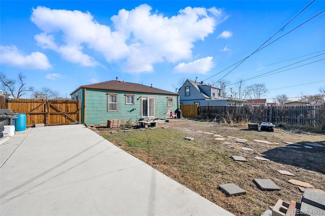 rear view of property featuring fence and a gate