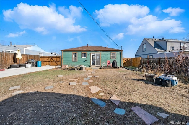 back of property with an outdoor structure, a fenced backyard, and a patio area