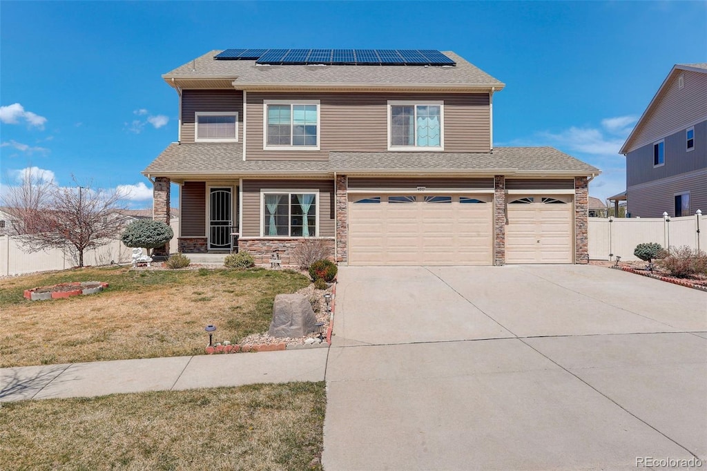 4971 Ceylon Way, Denver, CO 80249 - view of front of property featuring concrete driveway, fence, stone siding, a front lawn, and roof mounted solar panels