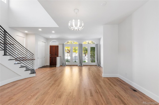 entryway with light wood-type flooring, french doors, and a notable chandelier