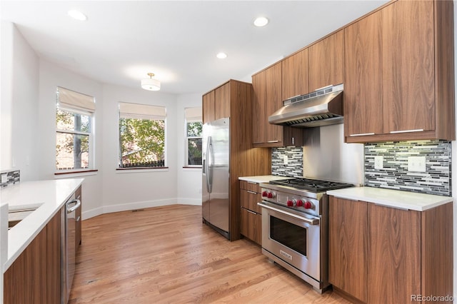 kitchen featuring light wood-type flooring, stainless steel appliances, and backsplash