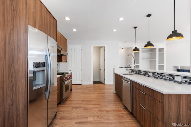 kitchen featuring tasteful backsplash, sink, light wood-type flooring, pendant lighting, and stainless steel appliances