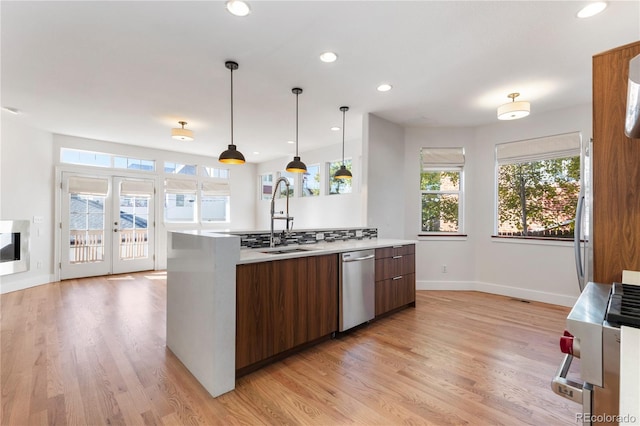 kitchen with hanging light fixtures, french doors, sink, light hardwood / wood-style floors, and stainless steel appliances